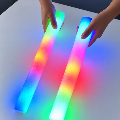 Two multicolour LED foam glow sticks held over a table