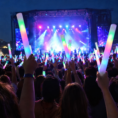 Glow sticks raised in a crowd at a stage show
