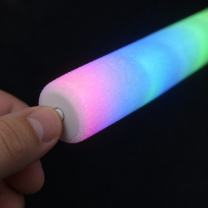Thumb pressing the small white button on the base of a foam glow stick